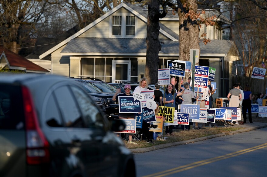 Supporters hold campaign signs on Super Tuesday outside of Pulaski Heights United Methodist Church on in Little Rock, Ark.