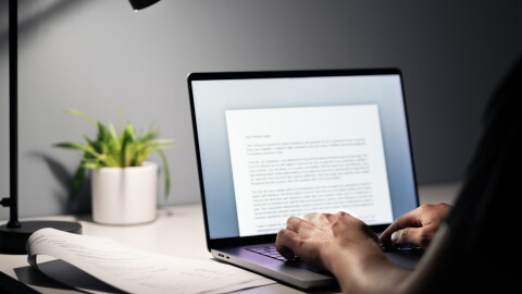 Man writing text document, essay or letter with laptop. Freelance writer, journalist or entrepreneur working late at night, overtime. Job seeker, cv resume and application. Dark home or office room.