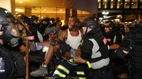 Police and protesters carry a seriously wounded protester into the parking area of the the Omni Hotel during a march to protest the death of Keith Scott Sept. 21, 2016 in Charlotte, N.C. (Brian Blanco/Getty Images)