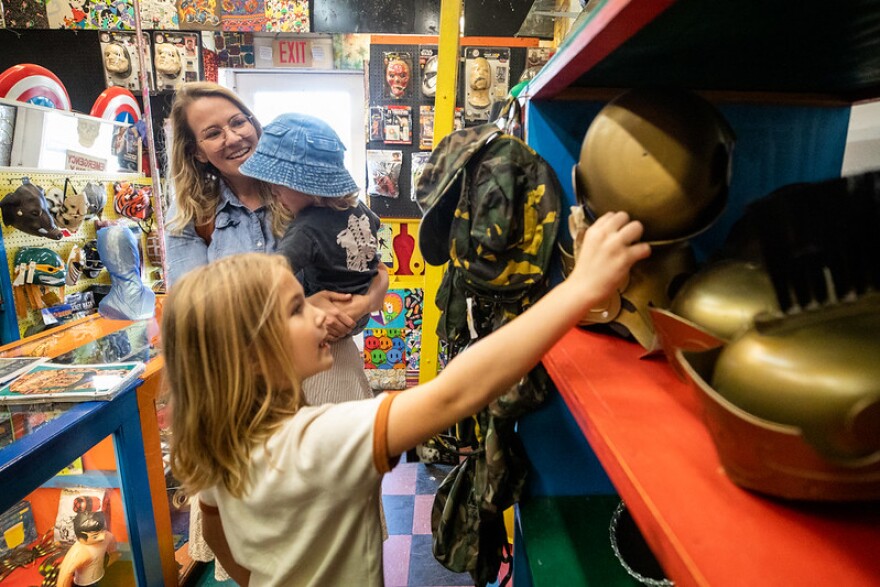 A child looks at masks on a shelf while his mother watches.