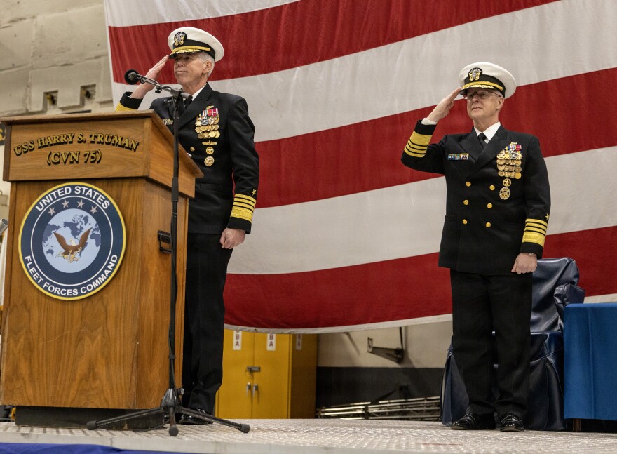 Adm. Karl Thomas, commander, U.S. Fleet Forces Command and Adm. Daryl Caudle, Chief of Naval Operations, salute during the assumption of command ceremony on the aircraft carrier USS Harry S. Truman.