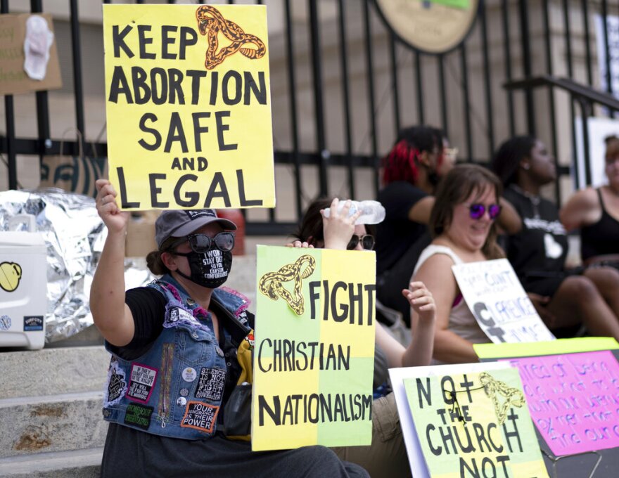 A  small group, including Stephanie Batchelor, left, sits on the steps of the Georgia state Capitol protesting the overturning of Roe v. Wade on June 26, 2022. A judge overturned Georgia’s ban on abortion starting around six weeks into a pregnancy, ruling Tuesday, Nov. 15, 2022 that it violated the U.S. Constitution and U.S. Supreme Court precedent when it was enacted.