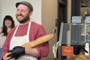 Co-owner of Good Hands Bread Co., Andrew Fisher, smiles brightly as he holds two freshly-baked baguettes at his new storefront.
