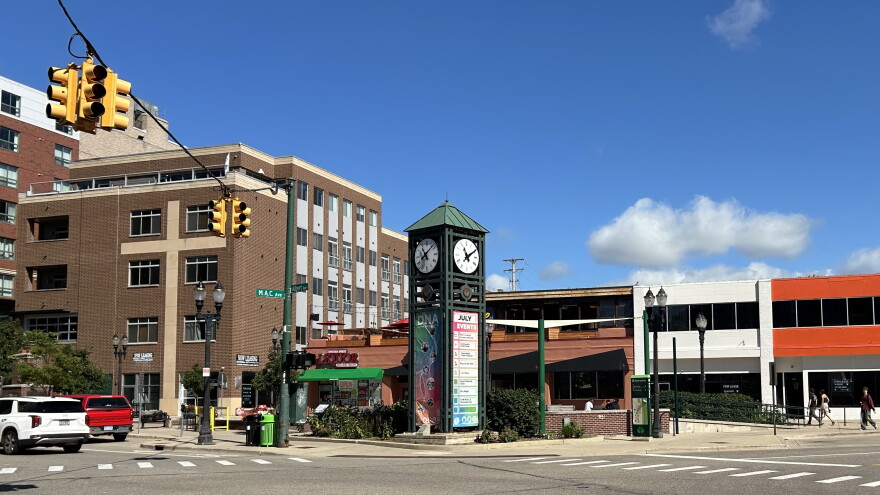 A green clocktower stands on a street corner