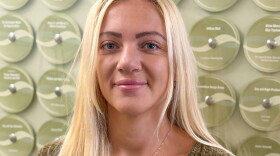 A woman stands in a hall smiling at the camera