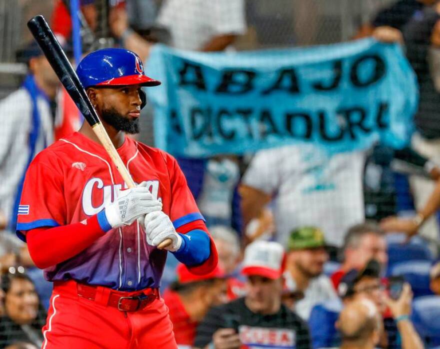 Cuba outfielder Luis Robert Jr. looks on as a protest hangs behind him during the game against the United States at the World Baseball Classic semifinal at loanDepot Park in Miami, Fla. on Sunday, March 19, 2023.