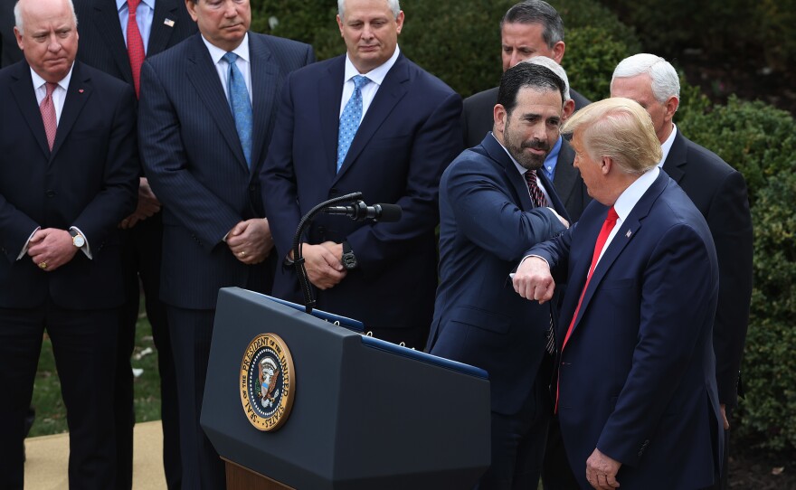 LHC Group Executive Vice President Bruce Greenstein bumps elbows with President Trump during the March 13 news conference.