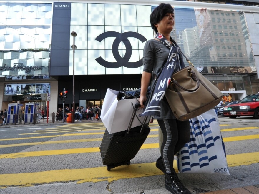 A mainland Chinese tourist crosses the street carrying multiple shopping bags in Hong Kong's Tsim Sha Tsui district. Tourists from the mainland spend more money in Hong Kong than tourists from all other countries combined.