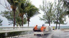 Landscapers ride in a truck along a stretch of road that's partially flooded from rain triggered by the arrival of Hurricane Matthew, in the eastern district of Nassau, Bahamas, Wednesday, Oct. 5, 2016. Forecasters said the storm was on track to roll directly over the capital city before nearing the Florida coast. (AP Photo/Craig Lenihan)