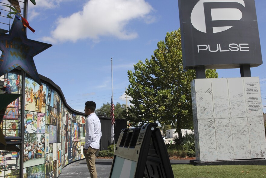 Brandon Wolf, a survivor of the Pulse nightclub shooting and activist, looks at the photos that are a part of the Pulse memorial in Orlando, Fla., on Sept. 9, 2022. 