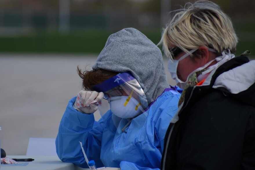 Employees doing COVID-19 testing wear considerable amounts of personal protective equipment.