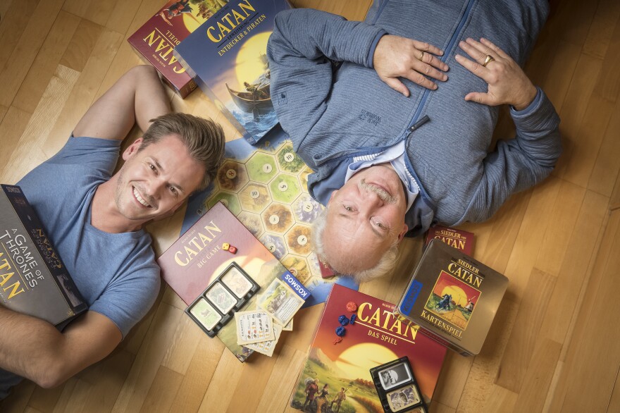 Klaus Teuber, creator of the popular board game Catan, with his son Benjamin Teuber, a managing director at Catan Inc. Celebrating the 25th anniversary of the game's launch, the elder Teuber has released an autobiography, <em>My Way to Catan</em>.