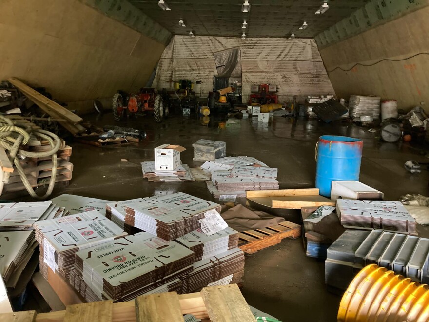 Equipment, packaging, and other items are strewn about a barn after floodwaters swept through.