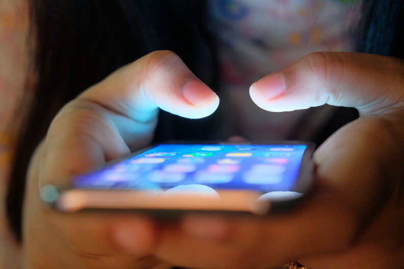 A child looks at social media apps on their phone.