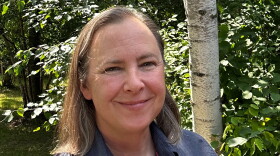 A woman smiling in front of birch trees
