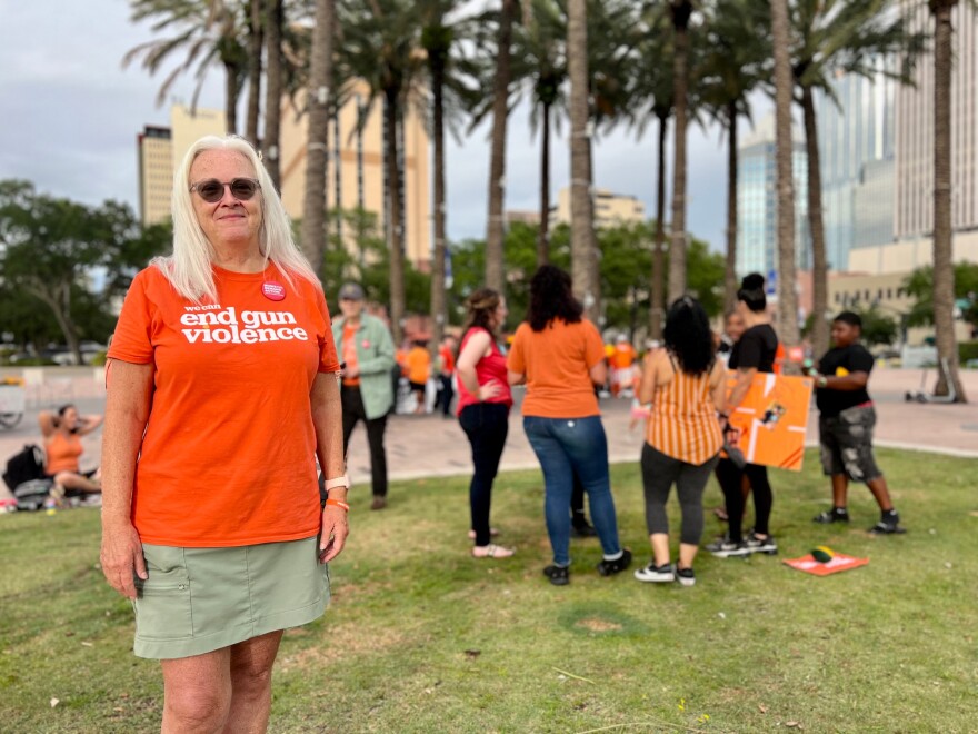 Woman in an orange shirt stands in Curtis Hixon Park in downtown Tampa at a gun violence awareness rally.