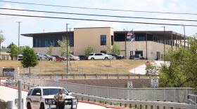 A sheriff's deputy stands in front of a sheriff's car at the entrance to Hill Country College Preparatory High School on Monday, March 30, 2026.
