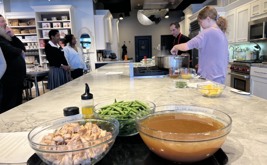 Students from Clark State stand to observe a fellow student help whisk butter into a large pot at the culinary center