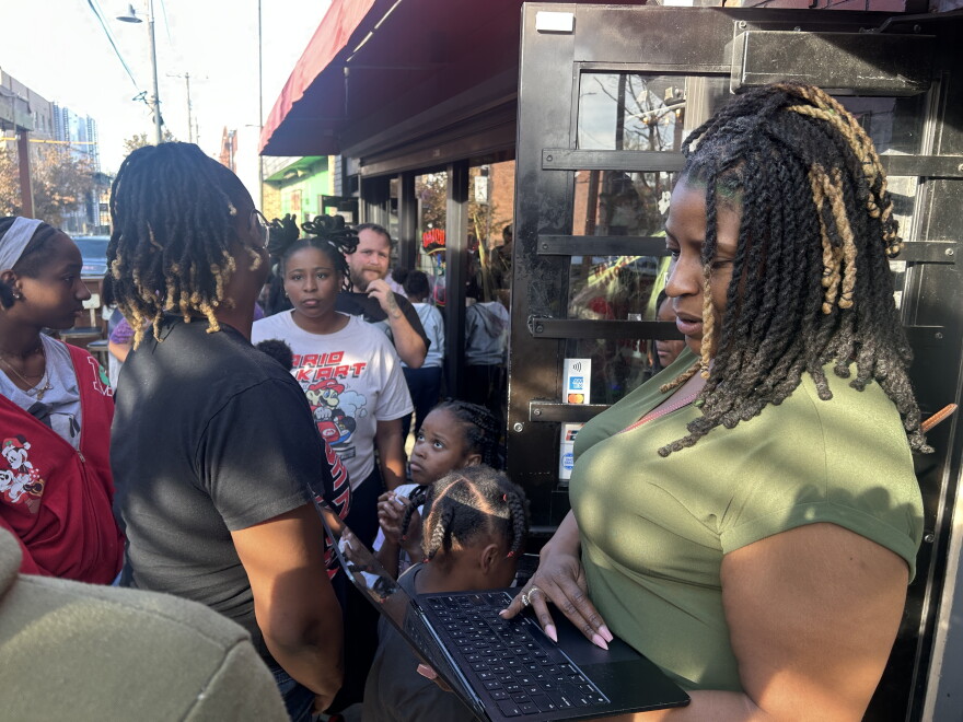 Makeda  Peterson is checking in families for costume distribution. 