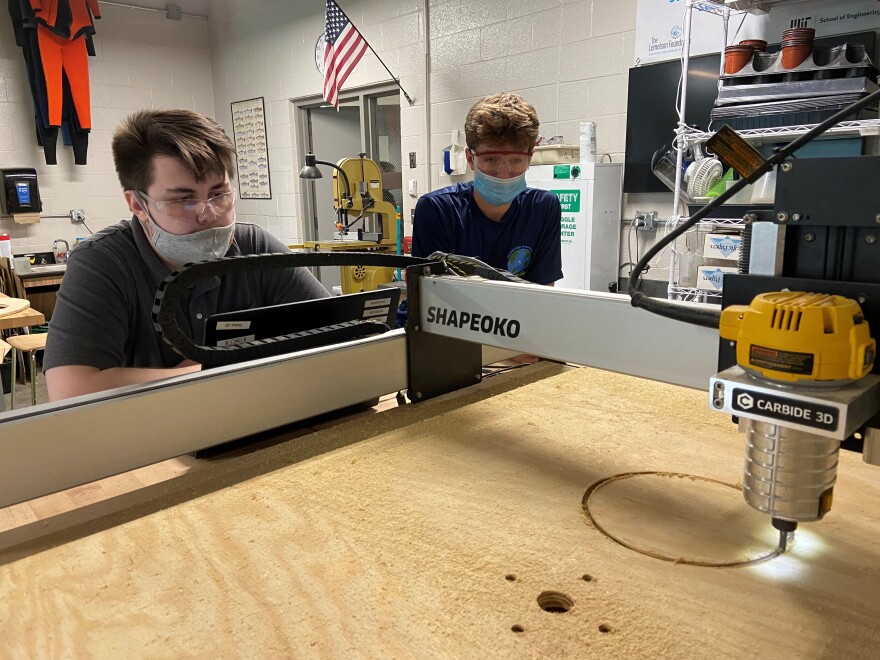 Stockbridge High School students Jack Hammerberg (left) and Brock Rochow watch as a CNC router cuts out a wheel.