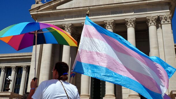 A person holds a transgender flag and a rainbow umbrella during a rally outside the Oklahoma State Capitol in Oklahoma City on March 14, 2024.