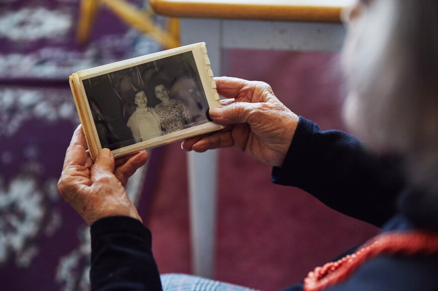 Smith holds a photograph of herself and her twin sister. Her home is decorated with many arrangements of family photographs.