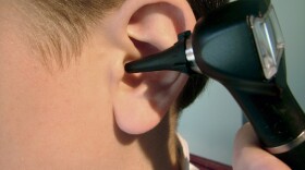 Doctor using otoscope instrument to check child's ear.