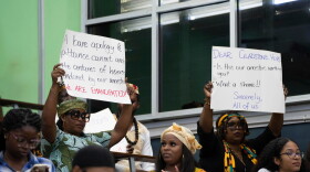 FILE - People hold signs during a speech by Charles Gladstone, a descendant of former plantation owner John Gladstone, as he delivers an apology on behalf of the Gladstone family at Georgetown University in Georgetown, Guyana, Friday, Aug. 25, 2023.