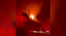 Flames are seen along a dark mountain and field