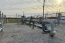 Metal pipes outside a gas plant go into the ground and connect to each other above ground. 