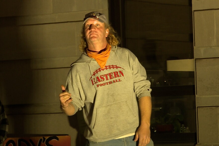 A photo of Harry Collins speaking in front of the large crowd at the "Hands Off Homeless" rally.
