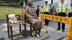 South Korean police stand guard beside a comfort woman statue in front of the Japanese embassy in Seoul in May. The Southern California city of Glendale will dedicate an identical statue on Tuesday.