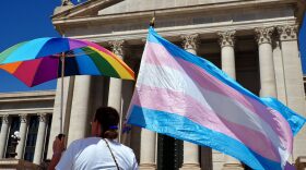 A person holds a transgender flag and a rainbow umbrella during a rally outside the Oklahoma State Capitol in Oklahoma City on March 14, 2024.