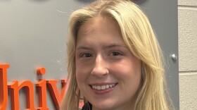 A headshot of Abbey Leibert, a young woman with blonde hair, smiling while standing in front of the WAER 88.3 sign.