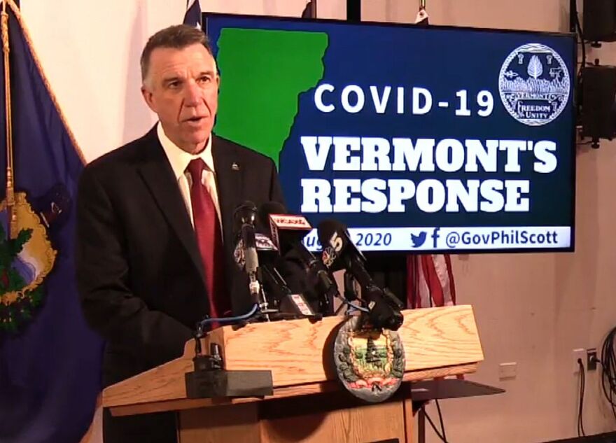 Gov. Phil Scott stands at a podium next to a screen