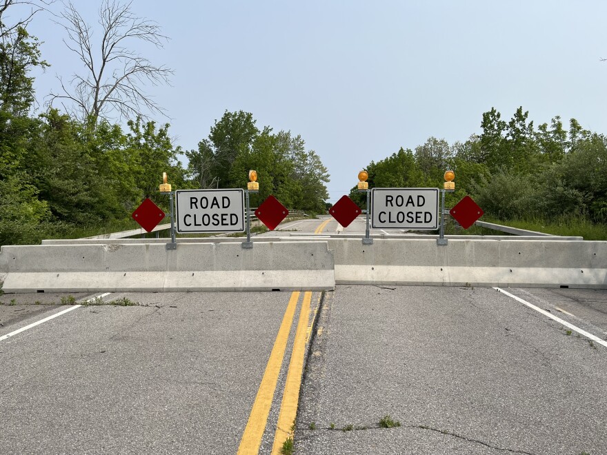 A pair of white signs reading "road closed" attached to two concrete barriers blocking the Gillett Road bridge in Ogden