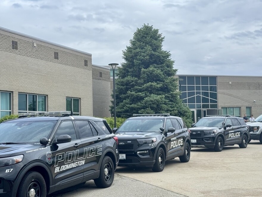 A row of black police cars and parked at the curb next to a building