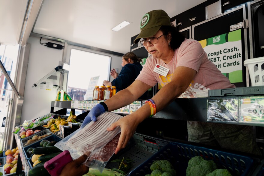 Evelyn Forbes, Operation Food Search’s MetroMarket Assistant Lead, hands packed meats to a food insecure community member outside the People's Health Center on Thursday, Oct. 9, 2025, in St. Louis’ West End neighborhood.