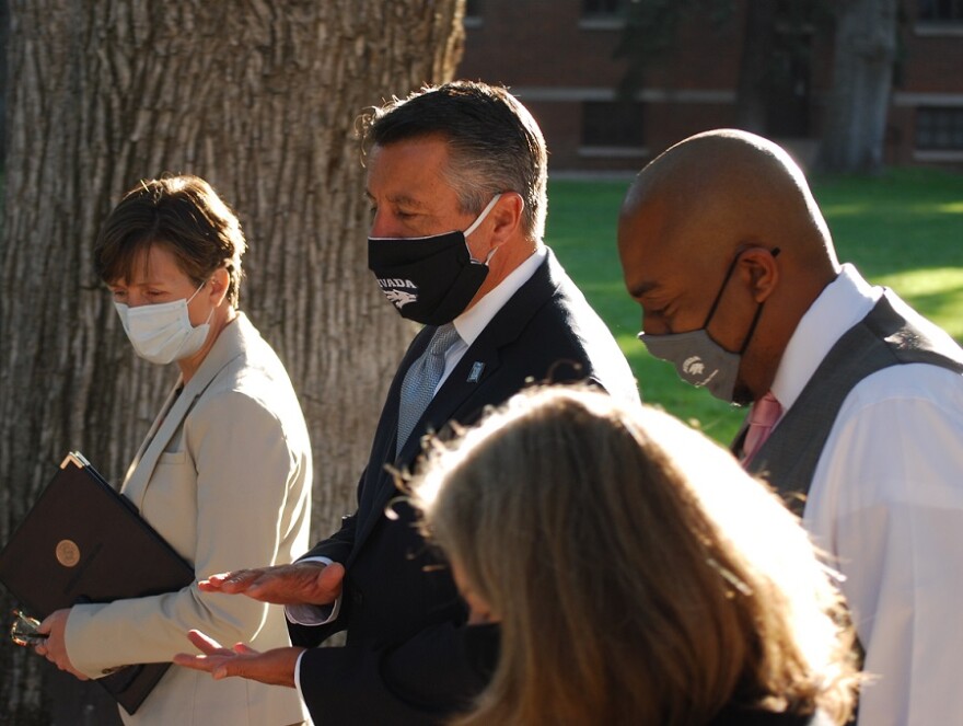 An image of UNR President Brian Sandoval wearing a mask while standing outside with other faculty members.