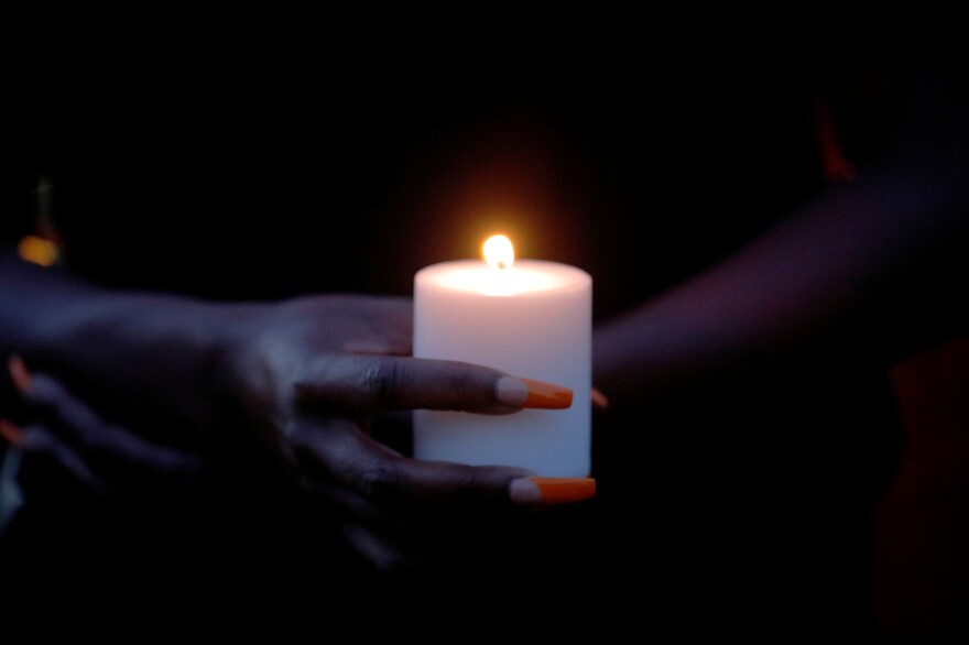 A woman holds a candle at a vigil.