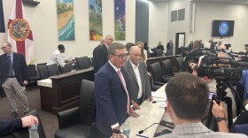 Florida legislative budget chairs surrounding by press in a Capitol committee room.
