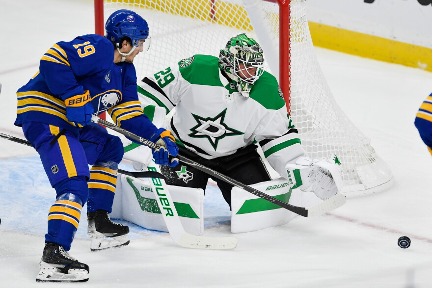 Buffalo Sabres center Peyton Krebs, left, and Dallas Stars goalie Jake Oettinger, right, reach for the puck during the third period of an NHL hockey game Thursday, Oct. 8, 2026, in Buffalo, N.Y. (AP Photo/Adrian Kraus)