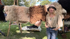 Artist Kelly Moody at the Mountain Harvest Festival standing in front of hides she tanned.