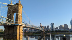  Part of the Downtown Cincinnati skyline is visible reflecting in the Ohio River, from near the base of the Roebling Suspension Bridge in Covington.