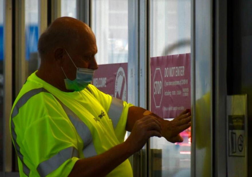 A worker at a Pilot Travel Center gas station in Greenfield, Indiana puts a stick on the door telling patrons not to enter if they feel symptoms associated with COVID-19.