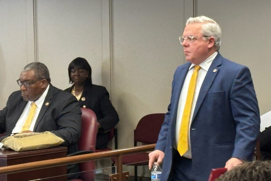 Alabama Representative Chip Brown walks into a committee meeting room holding a water bottle in his right hand.