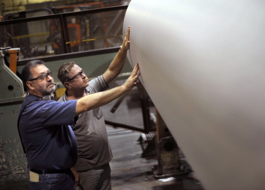 In this Nov. 21, 2011 photo, Rick Nicholson, front, and Louis Ouellette inspect a roll of paper on the operation floor of the East Mill in Millinocket, Maine. (AP Photo/Michael C. York)