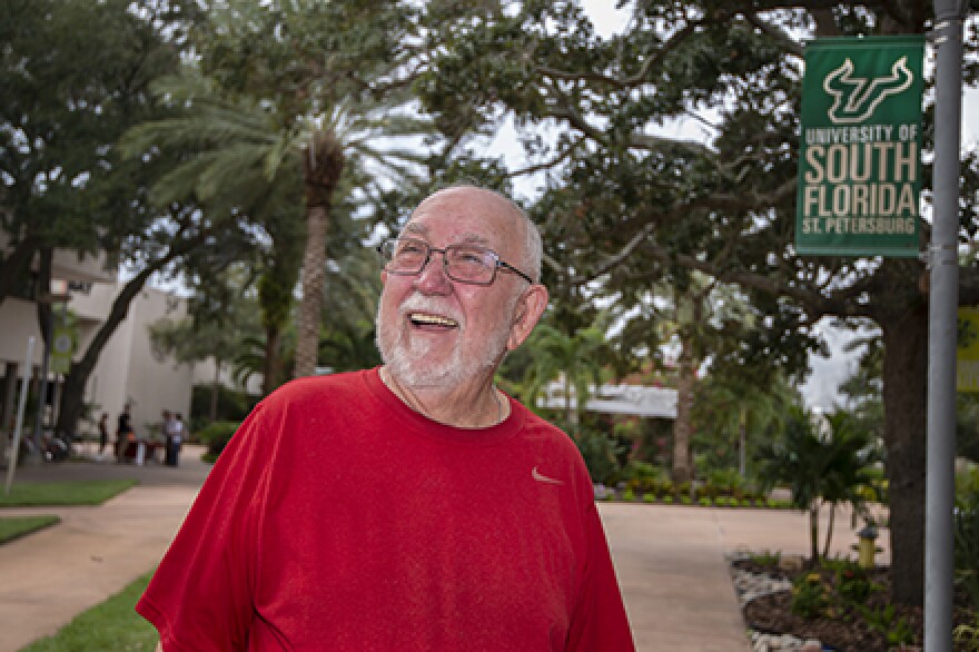 Man smiles on college campus.