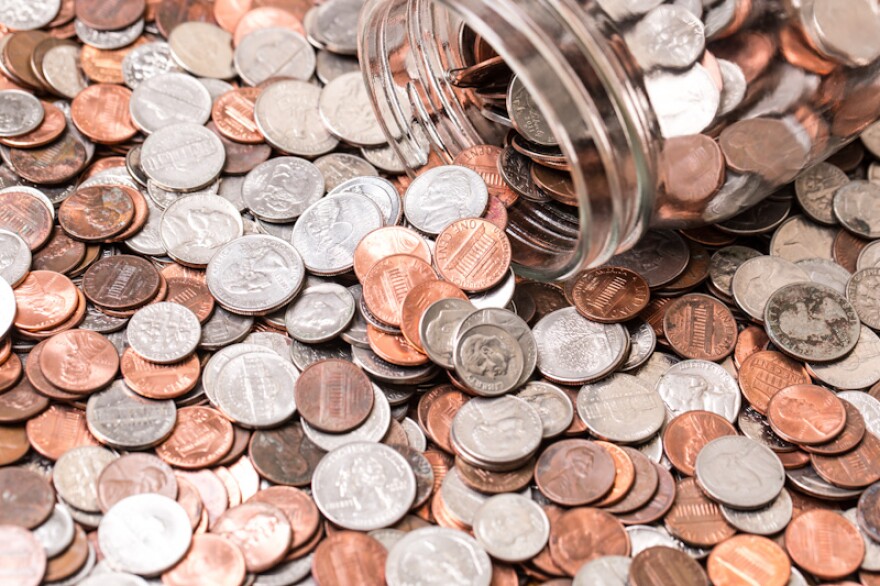 Close up of many different type of coins with jar.