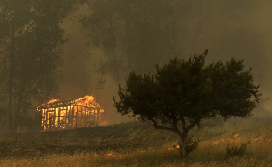 Fire engulfs a structure Thursday in Escondido, Calif. One of the nine wildfires burning in San Diego County suddenly flared Thursday afternoon and burned close to homes, triggering thousands of new evacuation orders.